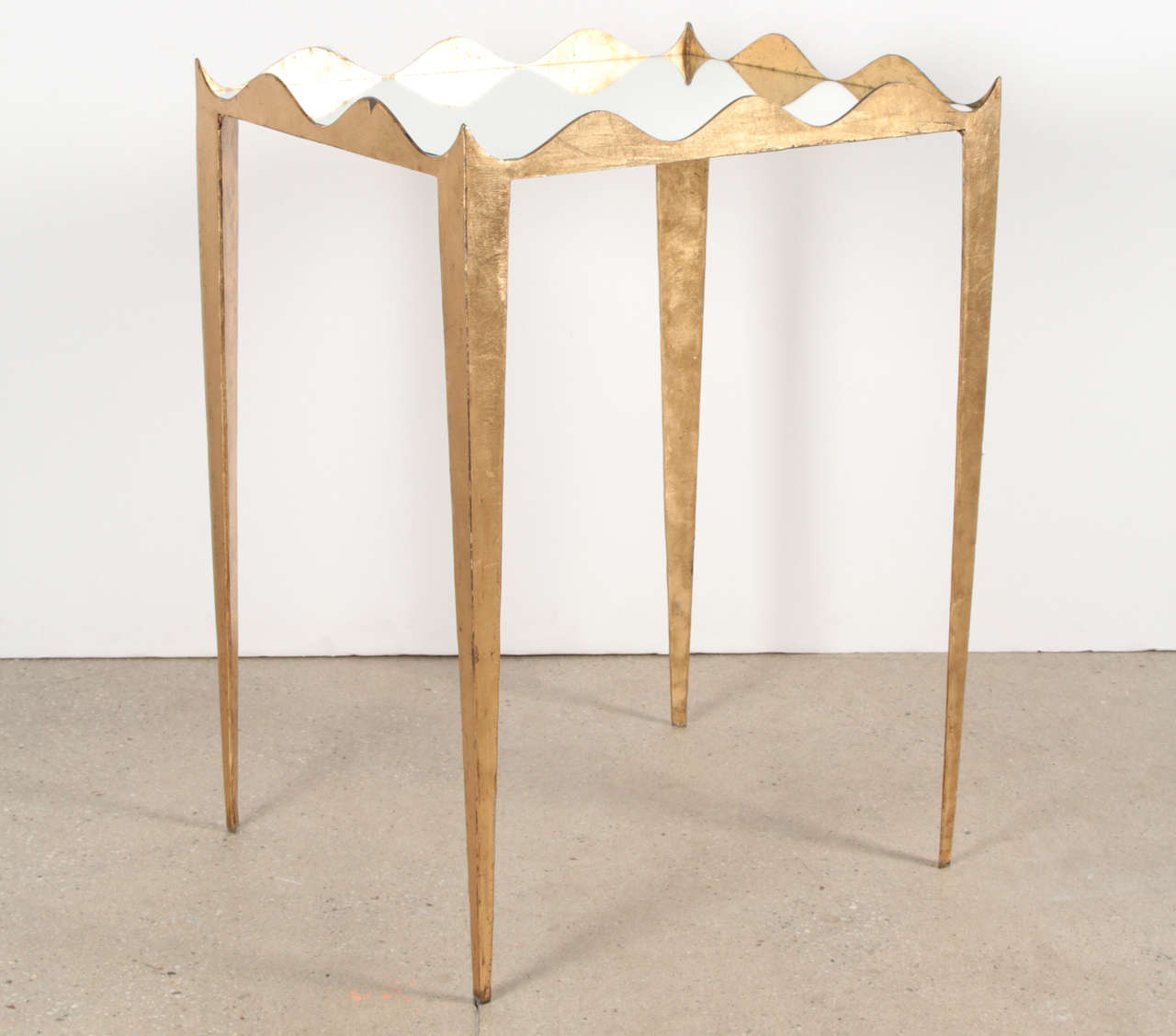 These gorgeous side tables were handcrafted in steel and hand gilded with 24-karat gold leaf which was then glazed and sealed to maintain its beauty. Scalloped edges, tapered legs and mirror tops add uniqueness to these elegant tables which can be